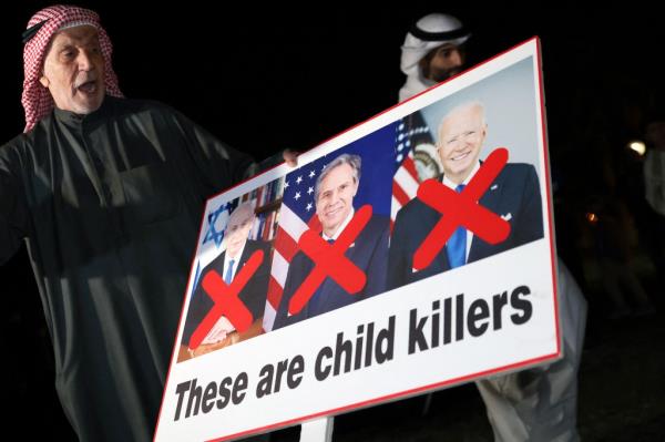 A Kuwaiti man holds a placard bearing the portraits of Israeli Prime Minister Benjamin Netanyahu (L), US Secretary of State Antony Bl<em></em>inken (C) and US President Joe Biden during a rally in solidarity with the people of Gaza at Iradah Square in Kuwait City on January 14, 2024, as the o<em></em>ngoing war between Israel and the Palestinian militant group Hamas enters its 100th day