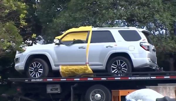 a silver suv on the back of a flatbed truck with a yellow tarp covering the inside of the driver's side door