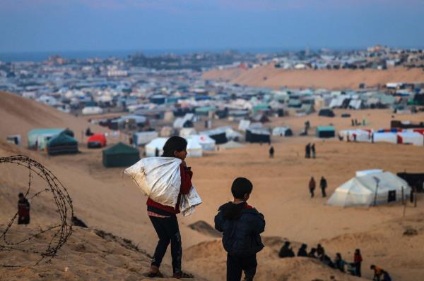 Displaced Palestinian children walk on a hill facing their makeshift camp in Rafah.